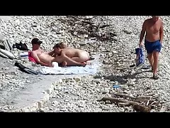 Pareja las mujeres desnudas follada en una playa pública como personas caminada cerca de